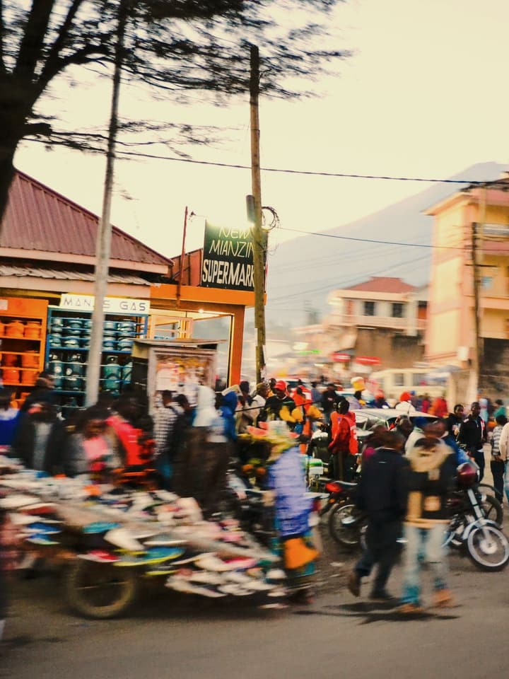 An evening street market in Arusha: a gas shop, a supermarket and a crowd of shoppers
