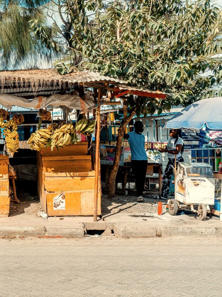 A roadside fruit stall hung with bunches of bananas
